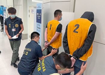 In this photo released by the Taiwan Criminal Investigation Bureau, police officers from the Taiwan Criminal Investigation Bureau search the bodies of two suspect who were deported from Bangkok and believed to be involved in scam cases in Cambodia as they arrive back at the Taoyuan International Airport in Taiwan on Thursday, Aug. 18, 2022. Taiwan is seeking to free more than 300 of its citizens lured to Cambodia by organized crime groups promising high wages for tech jobs, but then forcing them into call centers aiming to scam mainland Chinese into making payments for non-existent government fees or investment opportunities. (Taiwan Criminal Investigation Bureau via AP)