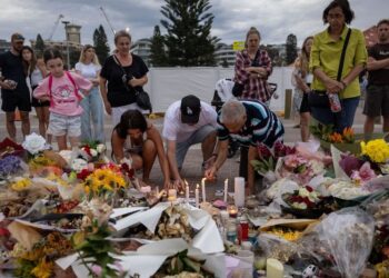 People light candles among the floral tributes for victims and survivors of a deadly mass shooting during a Jewish Hanukkah celebration at Bondi Beach on December 14, in Sydney, Australia, December 21, 2025. REUTERS/Eloisa Lopez