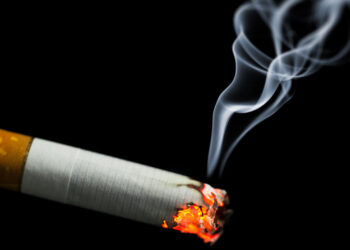 burning cigarette with smoke on black background