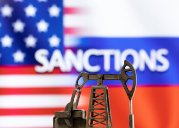 FILE PHOTO: A model of a pump jack is seen in front of the displayed word "Sanctions",  U.S. and Russia flag colours in this illustration taken March 8, 2022. REUTERS/Dado Ruvic/Illustration