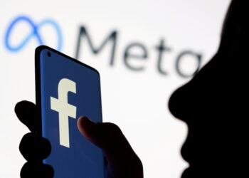 FILE PHOTO: Woman holds smartphone with Facebook logo in front of a displayed Facebook's new rebrand logo Meta in this illustration picture taken October 28, 2021. REUTERS/Dado Ruvic/Illustration/File Photo