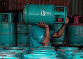 A worker carries an empty Petronas gas cylinder on his shoulder at a shop in Ampang, in the suburbs of Kuala Lumpur, on February 29, 2016. Malaysian state energy firm Petronas was expected to announce its quarterly earnings later on February 29.   AFP PHOTO / MOHD RASFAN