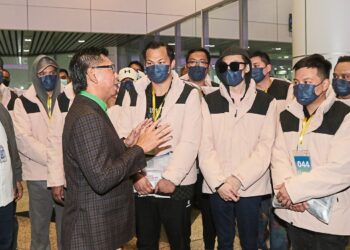 Deputy Foreign Affairs Minister Datuk Mohamad Alamin (third left, green shirt inside) giving an advice to the part of the scam victims (light brown jacket) near the international arrival door of KLIA on Friday morning. — IZZRAFIQ ALIAS/The Star