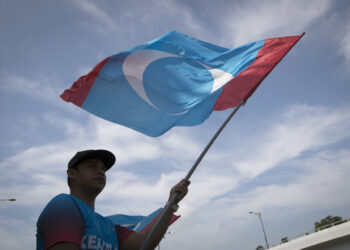 Supporter of Peoples Justice Party waves party flag outside palace in Kuala Lumpur, Malaysia, Thursday, May 10, 2018. Official results from Malaysia's national election show the opposition alliance led by the country's former authoritarian ruler Mahathir Mohamad won a majority in parliament, ending the 60-year rule of the National Front. (AP Photo/Vincent Thian)