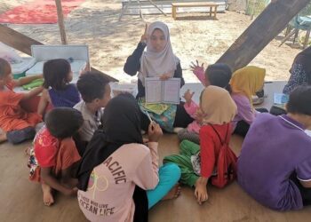 A volunteer teacher teaching s group of stateless children at Sekolah Alternatif.