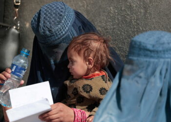 FILE PHOTO: A displaced Afghan woman holds her child as she waits with other women to receive aid supply outside an UNCHR distribution center on the outskirts of Kabul, Afghanistan October 28, 2021. REUTERS/Zohra Bensemra