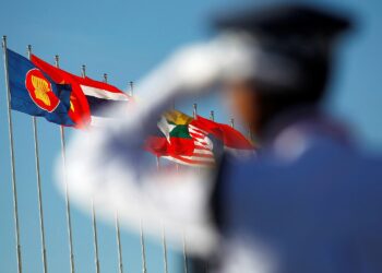 FILE PHOTO: A police officer stands near national flags of ASEAN counties flags during the 25th ASEAN Summit in Myanmar International Convention Centre in Naypyitaw November 12, 2014.    REUTERS/Soe Zeya Tun/File Photo