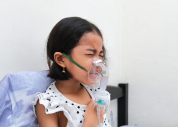 Asian kid in nebulizer treatment when suffering chest tightness