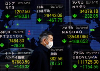 FILE PHOTO: A man walks past an electronic board displaying Japan's Nikkei index and various countries' stock market index prices outside a brokerage in Tokyo, Japan, February 22, 2022. REUTERS/Kim Kyung-Hoon
