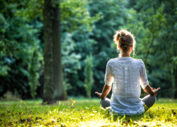 Young blonde woman meditating in the park