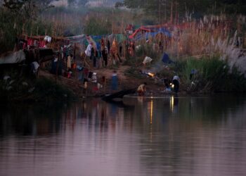 Refugees, who have fled a flare-up in fighting between the Myanmar army and insurgent groups and settled temporarily on the Moei River Bank, are seen on the Thai-Myanmar border, in Mae Sot, Thailand, January 7, 2022. REUTERS/Athit Perawongmetha