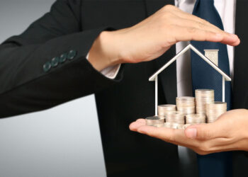 Growing coins house on stack coins in hand. Concept of Investment propert and finance investment concep