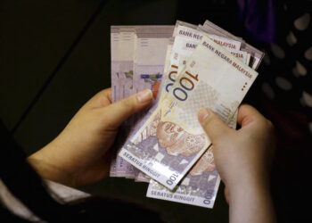 A customer counts her ringgit notes outside a money changer at the central business district in Singapore in this August 25, 2015 file photo.  Malaysia's ringgit jumped more than 5 percent to a five-week high on October 7, 2015 on stop-loss dollar selling and higher local stocks.  The ringgit, the worst performing Asian currency so far this year, surged as much as 5.2 percent to 4.1600 per dollar, its strongest since Sept 1.     REUTERS/Edgar Su/Files