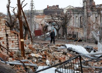 A man walks near damaged buildings in the course of Ukraine-Russia conflict in the southern port city of Mariupol, Ukraine April 22, 2022. REUTERS/Alexander Ermochenko