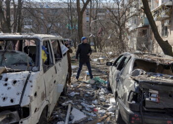A man walks near destroyed cars in a residential district that was damaged by shelling, as Russia's invasion of Ukraine continues, in Kyiv, Ukraine, March 18, 2022. REUTERS/Marko Djurica